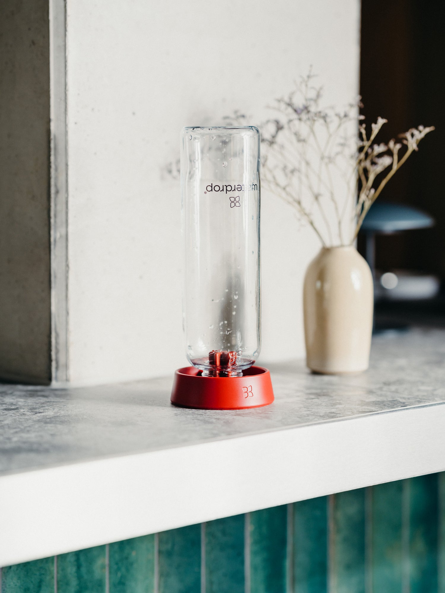 A glass jar and a vase with dried flowers on a counter, illustrating waterdrop®'s focus on stylish hydration solutions.