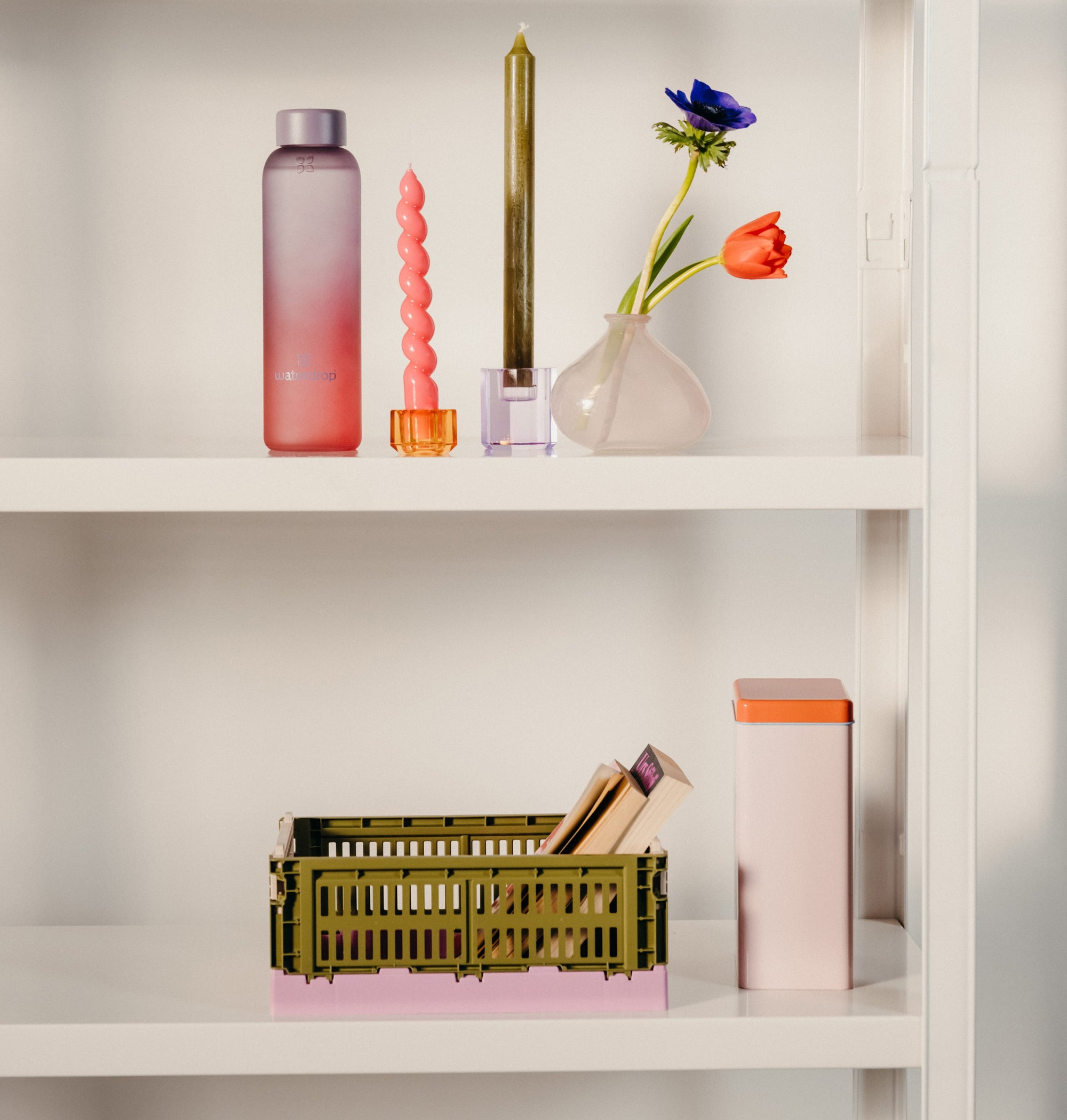 A shelf displaying a glass vase with flowers and a lit candle, suitable for enhancing a hydration-themed home décor.