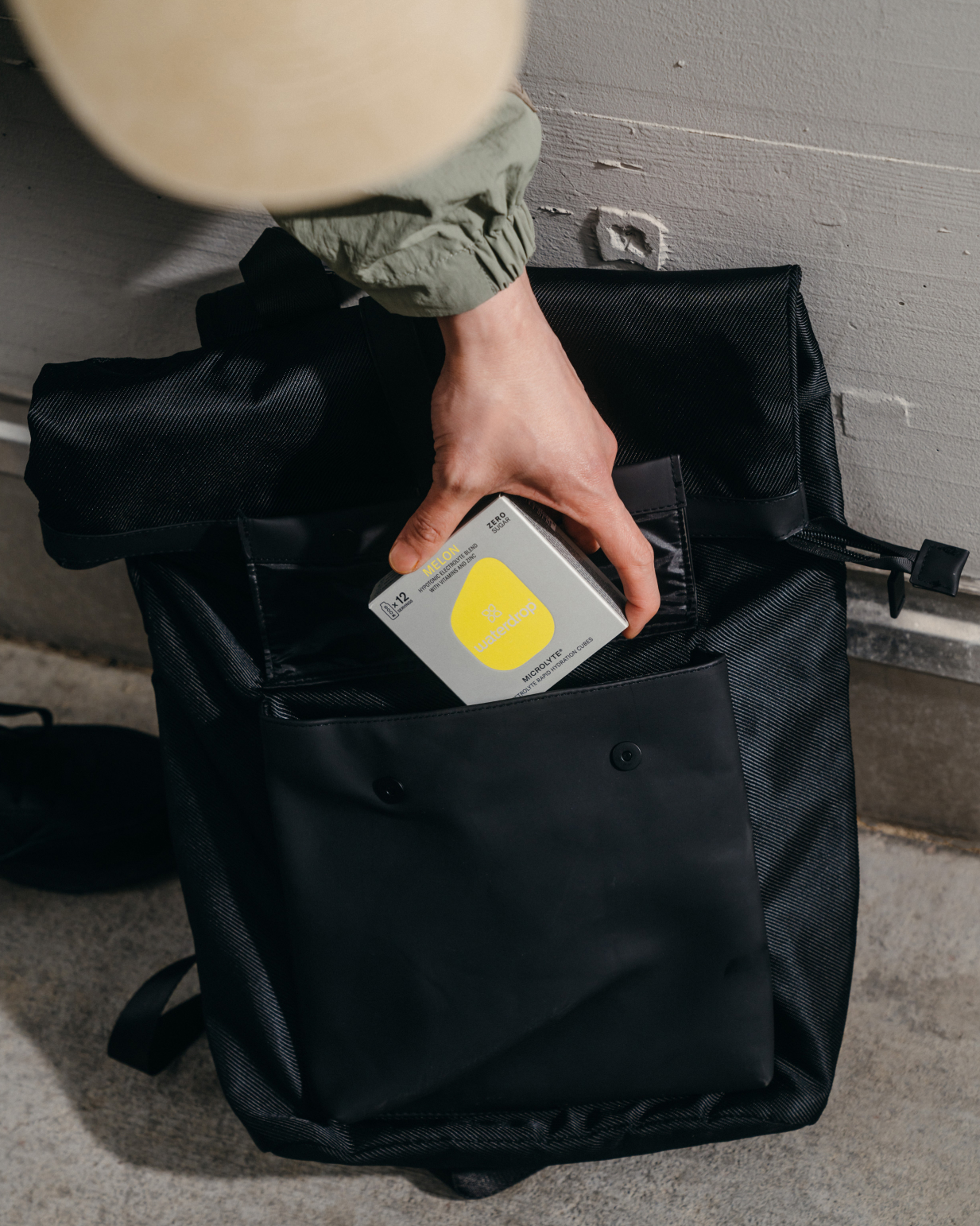 Hand holding a black bag containing a Microlyte Set 12-pack from waterdrop, featuring four electrolyte flavors: Berry, Blueberry, GRAPEFRUIT microdrink, and Melon.