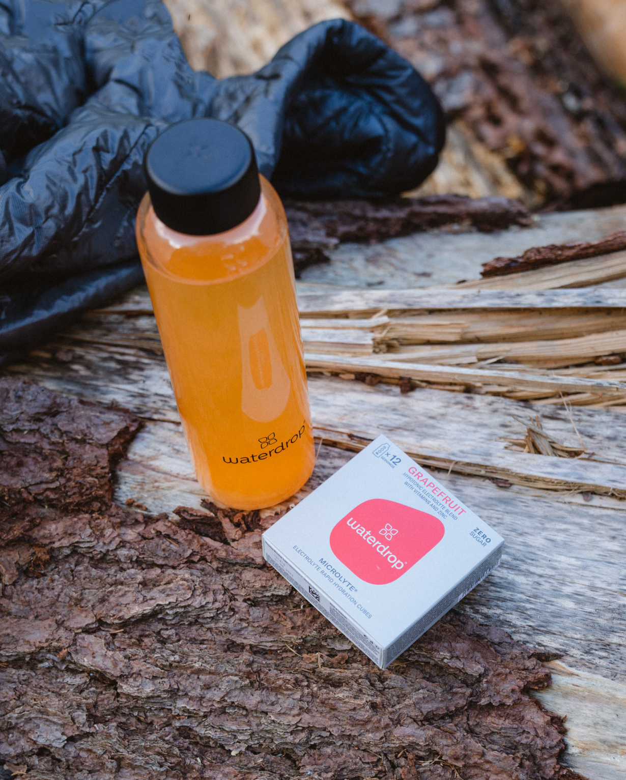 Microlyte Set on tree next to a white 12-pack, showcasing four flavors for hydration and performance enhancement.