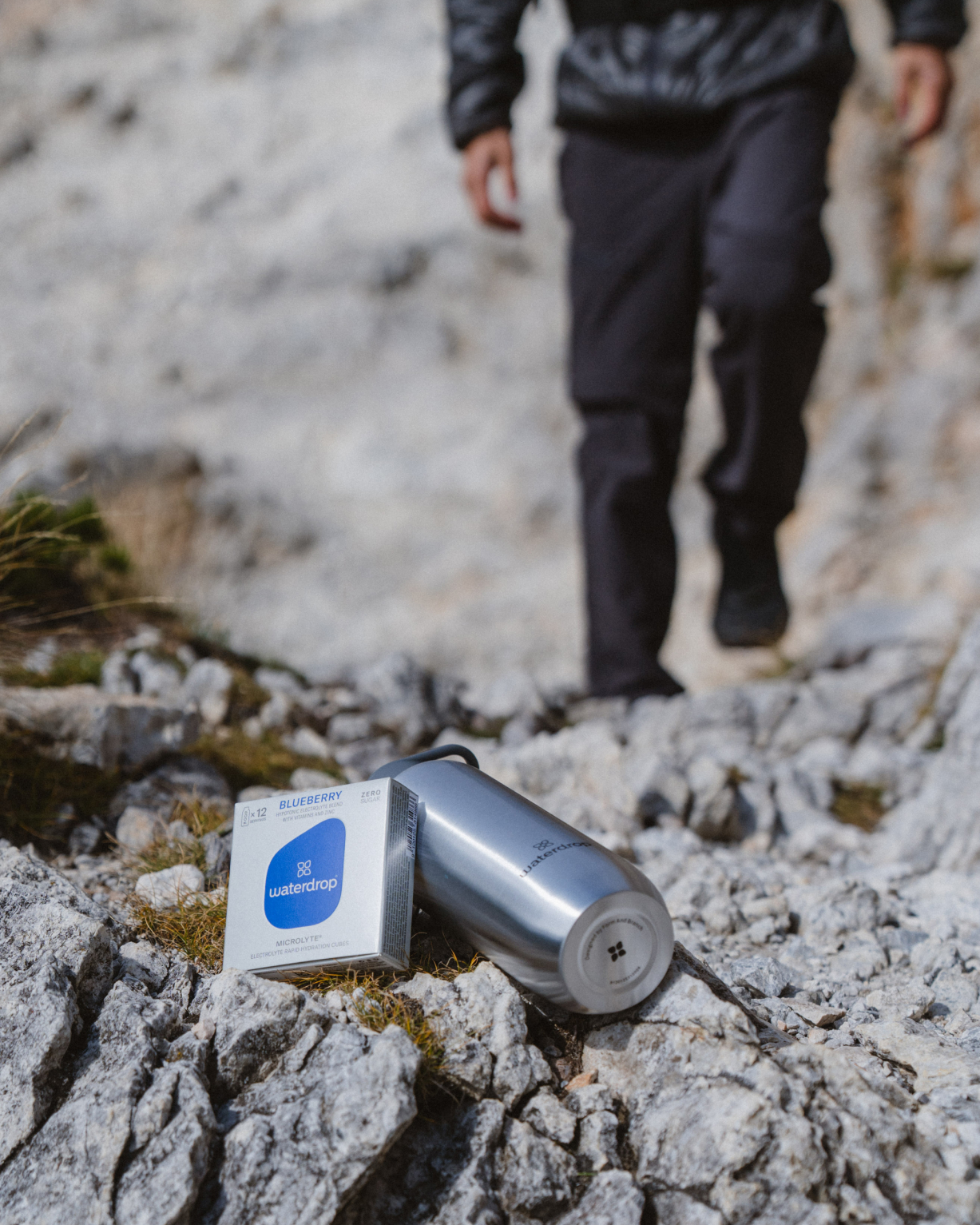 Microlyte Set on rocky terrain next to a white box, showcasing four flavors for hydration and performance enhancement.