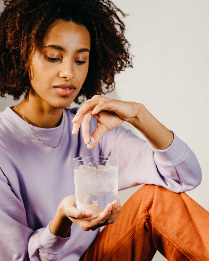 Woman holding a glass of water, showcasing the 30 Days Hydration Set featuring 60 Microdrinks for long-term hydration goals.