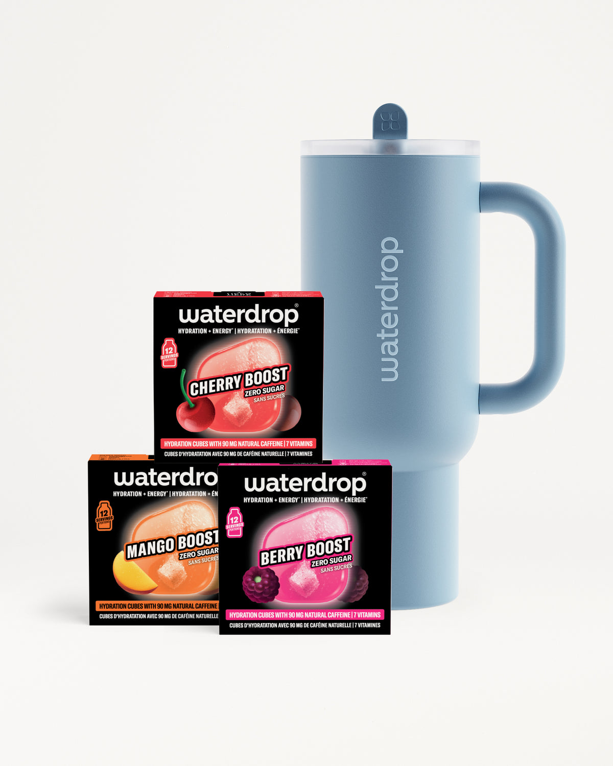 Blue insulated mug with lid and handle beside three small black boxes with colorful fruit imagery.