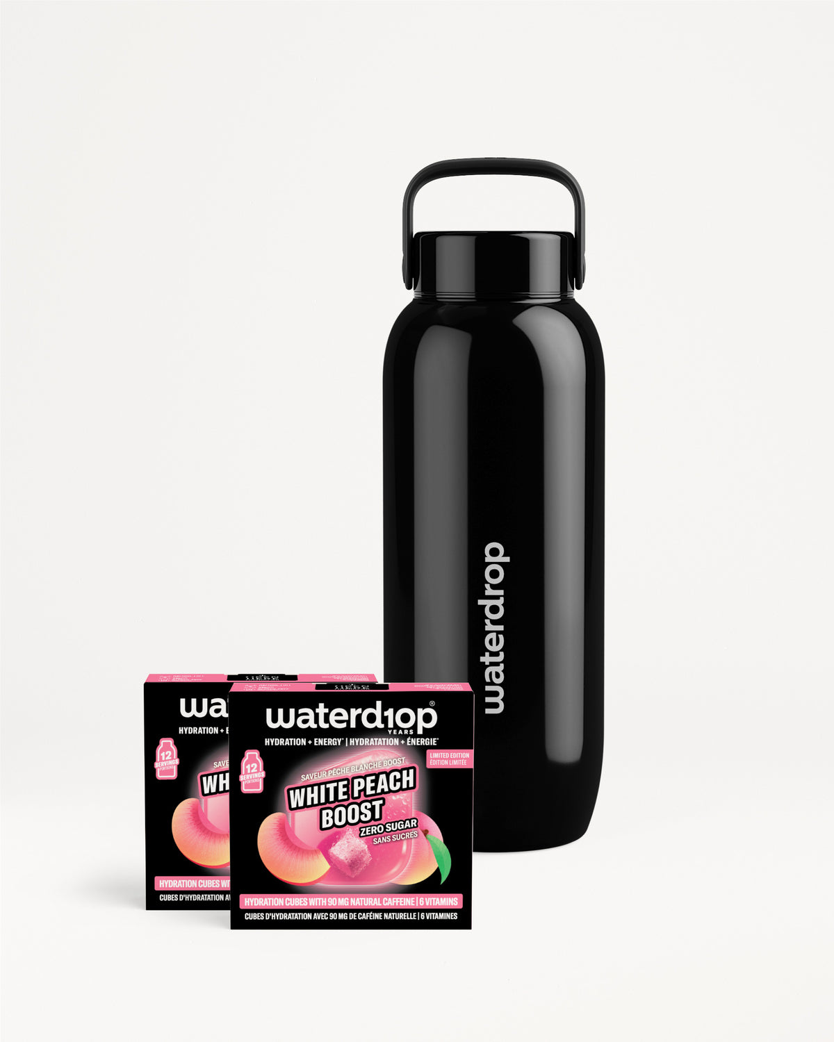 Black stainless steel reusable water bottle with a carrying handle, shown beside two small flavor boxes.