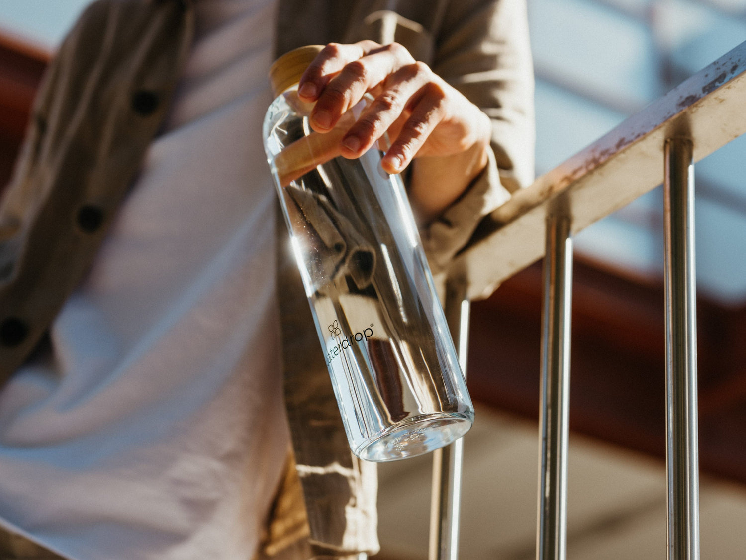 A person holding a waterdrop® branded glass water bottle, emphasizing hydration solutions.