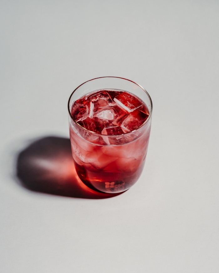 Glass of red liquid with ice, part of the 30 Days Hydration Set by waterdrop®, featuring 60 Microdrinks for long-term hydration habits.