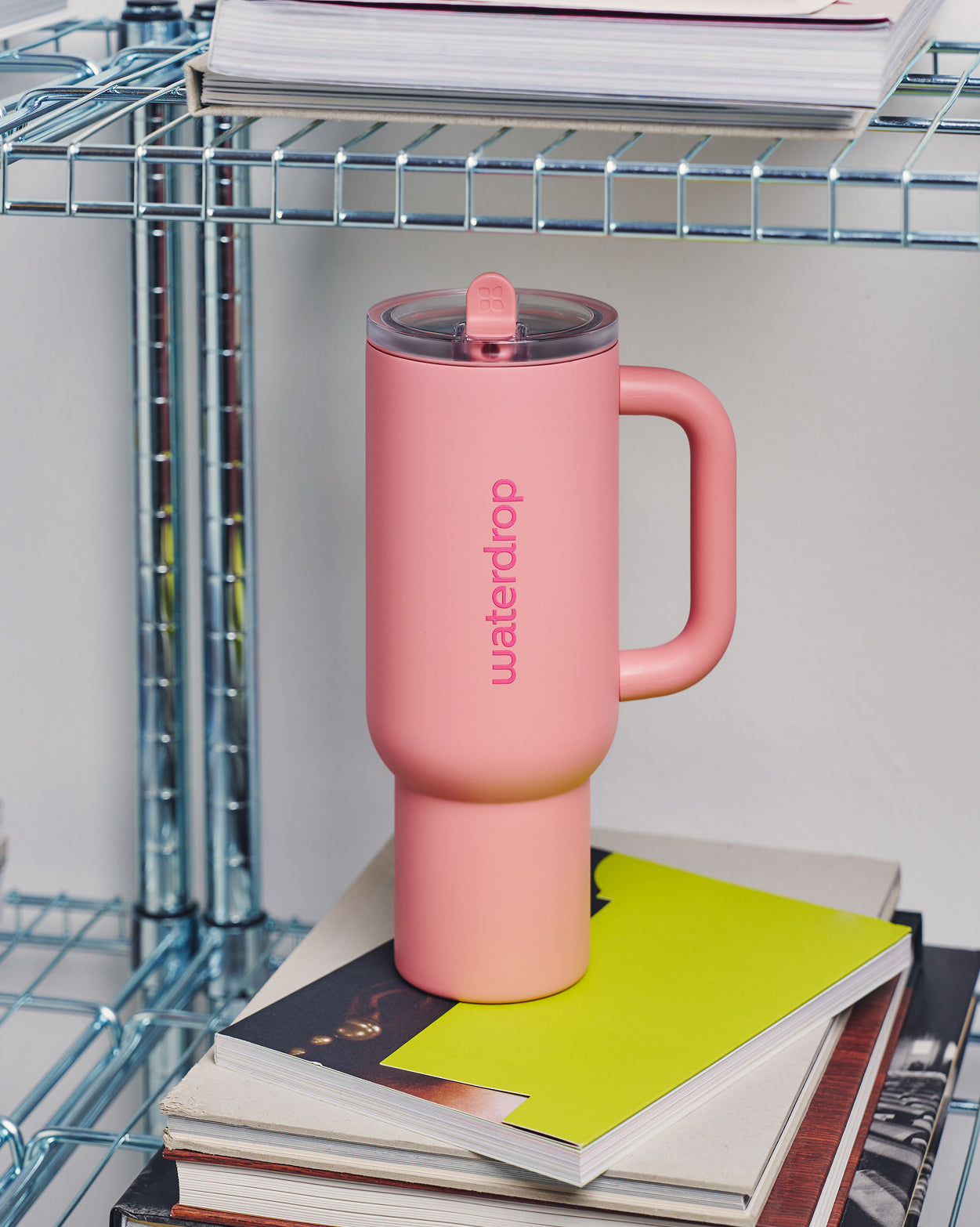 Social Mode Set: pink insulated travel mug on books.