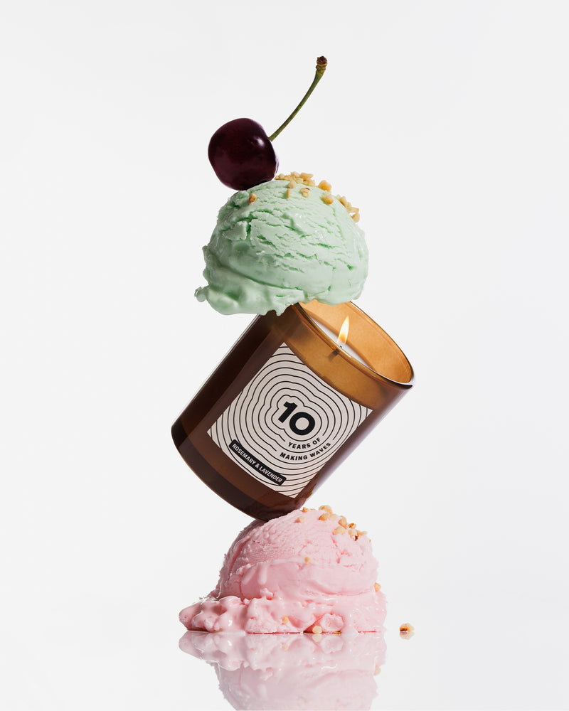A brown candle balanced between two pastel ice cream scoops, topped with a cherry.