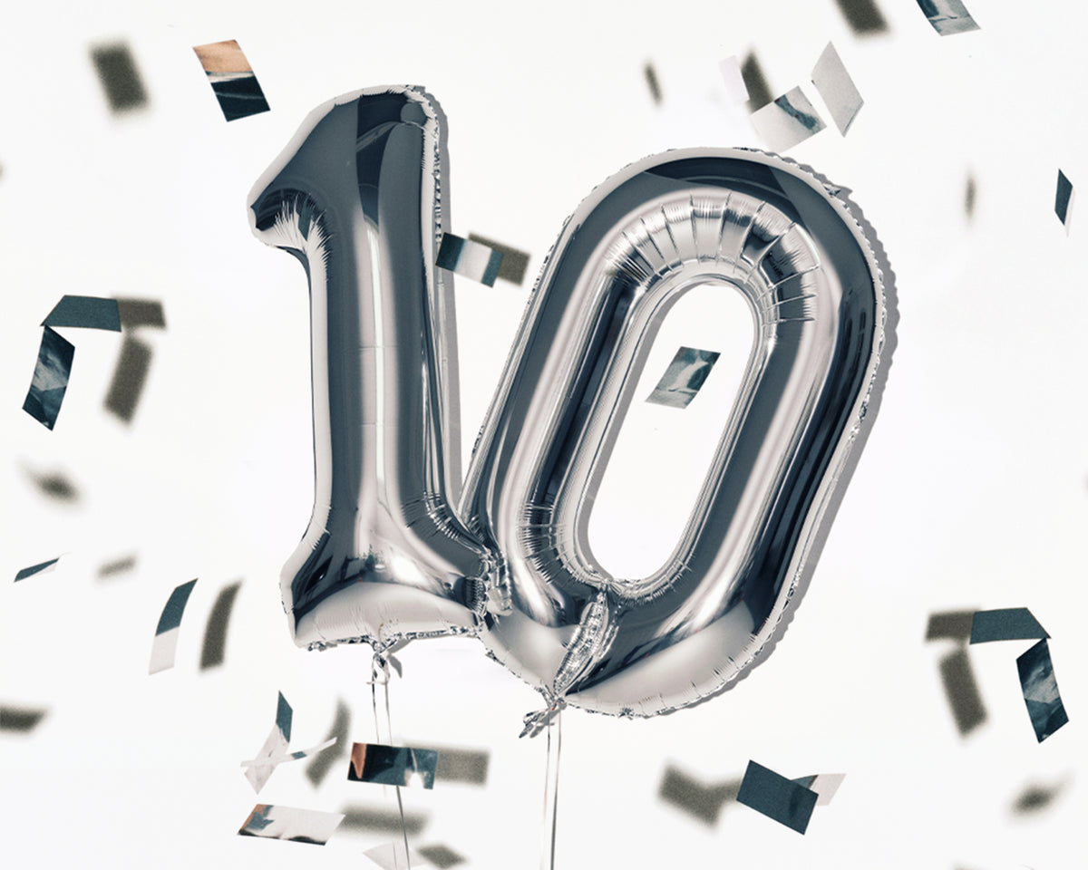 Silver foil balloons shaped as the number 10 with scattered confetti.