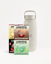 Light gray reusable bottle with a handle beside three flavor mix boxes.