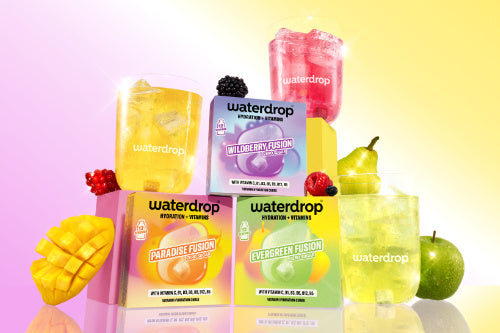 Colorful boxed and bottled fruit-flavored beverages arranged in a pyramid with glasses against a pastel gradient background.