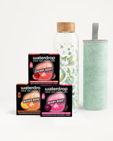 Set of three Waterdrop flavor boost boxes with a glass infuser bottle and a light green tumbler.
