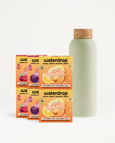 Six orange drink-mix boxes arranged beside a light green bottle with a cork cap.