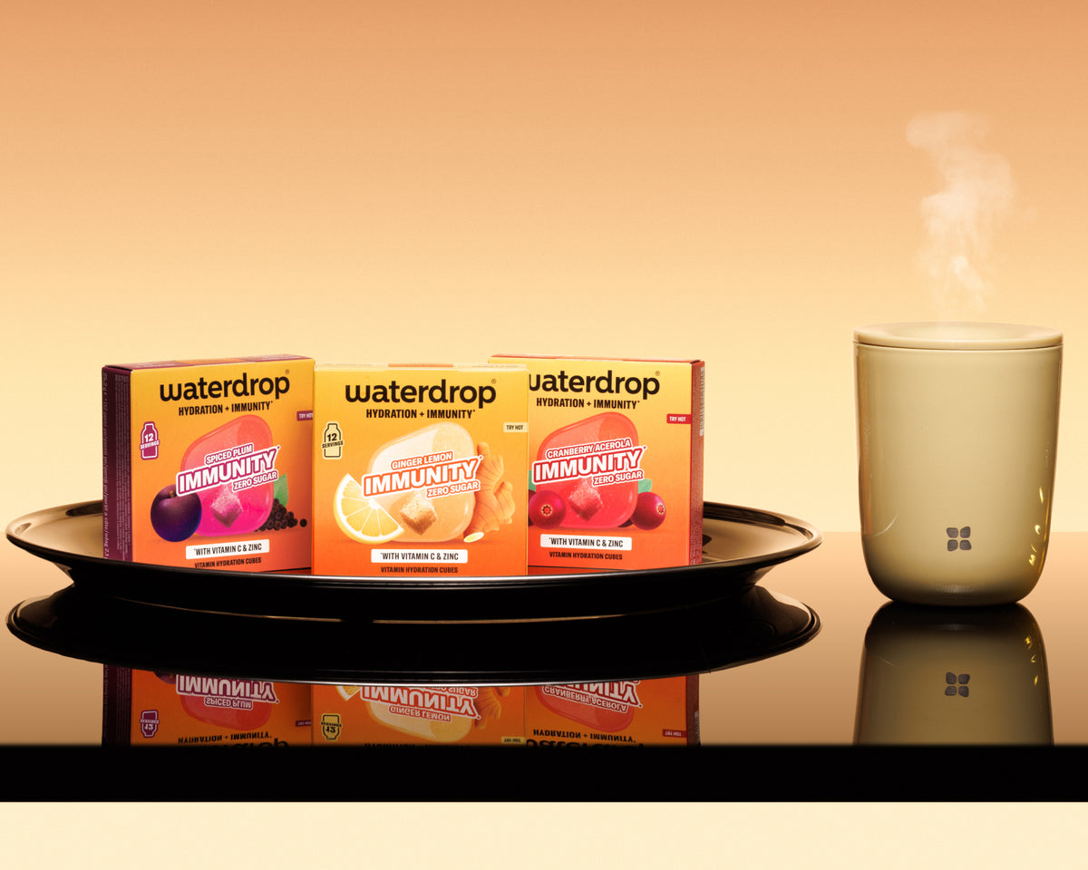 Three orange boxes on a black tray with a white steam-emitting diffuser to the right against a warm gradient background.
