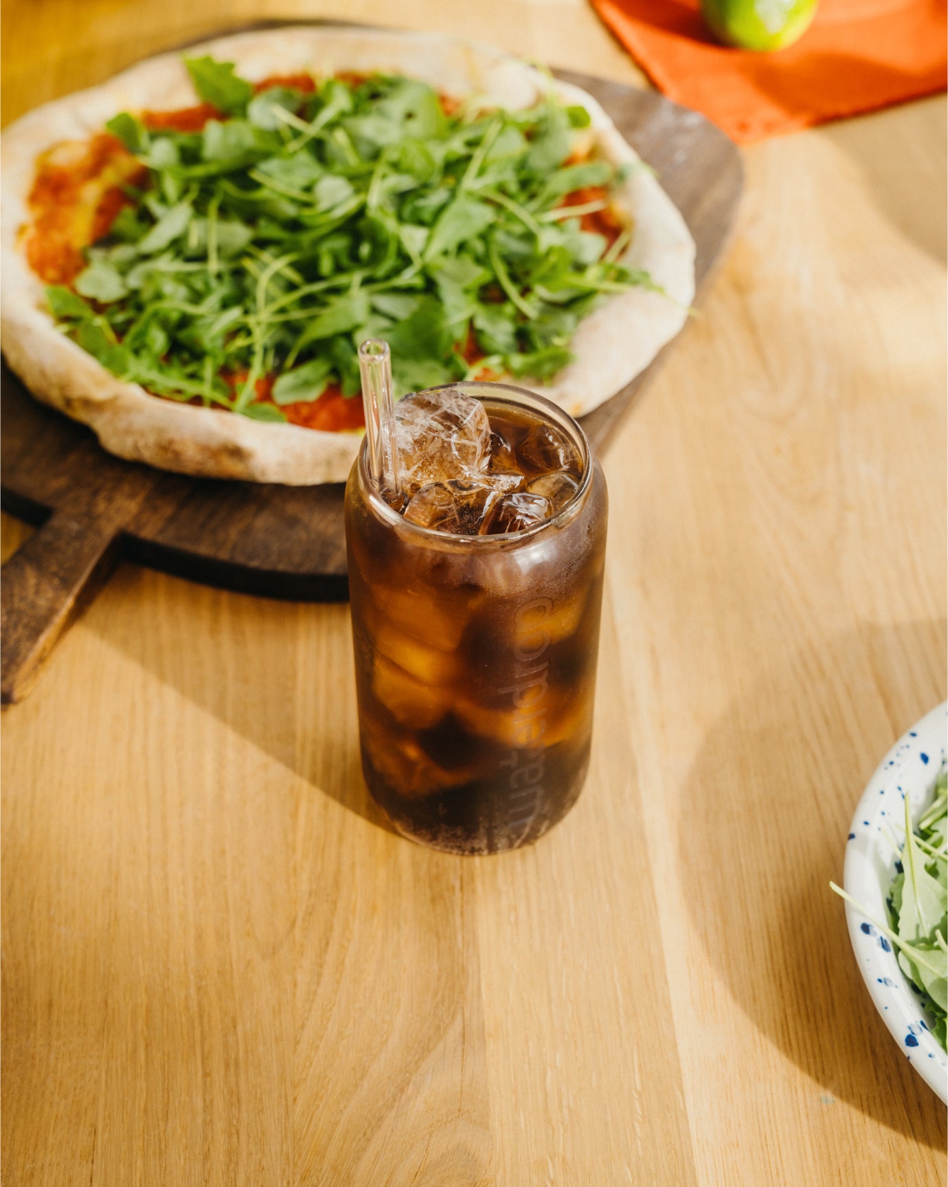 COLA Glass Can with iced beverage on wooden table.