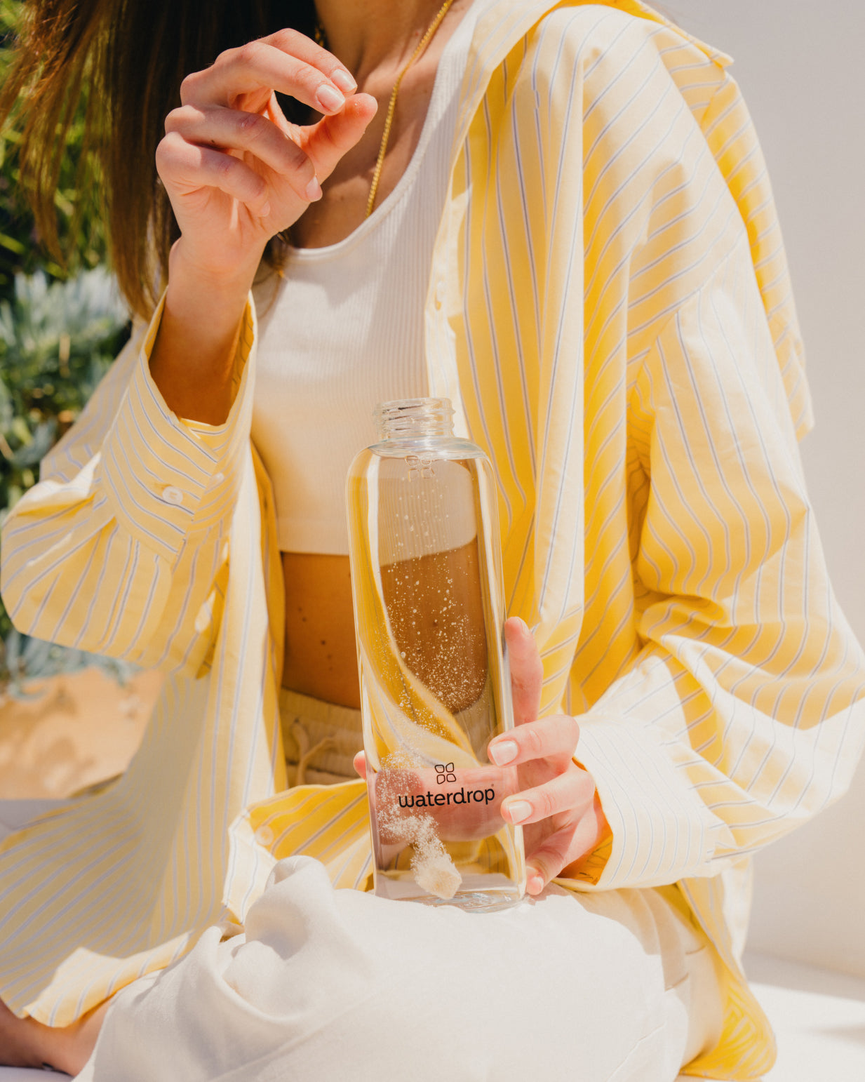 Woman holding a bottle of ICE TEA LEMON, a refreshing drink made with lemon and green tea, ready to be dissolved in water.