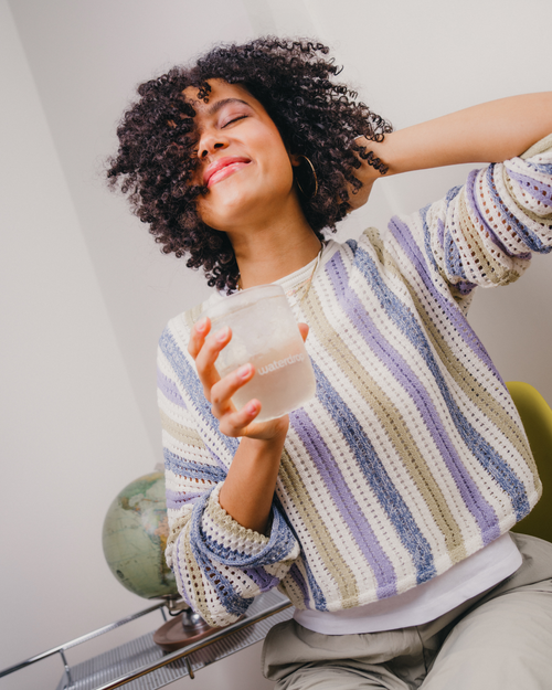 A woman holding a glass of water, highlighting the waterdrop® PASSION FRUIT flavor, known for its fruity, tropical essence and hydration benefits.